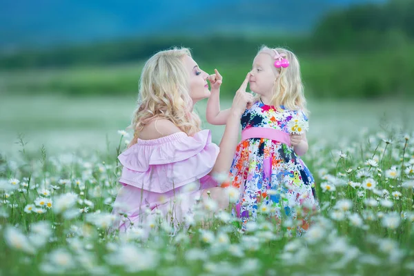 Блондинка мати з милою маленькою донькою в білих барвистих рожевих сукнях в ромашковому полі, літній час Насолоджуючись проводити разом щасливе дитинство — стокове фото