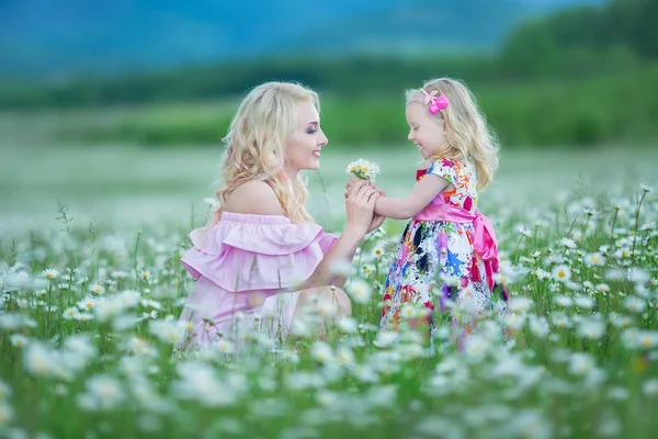 Blond mother with cute little daughter wearing white colourful pink dresses in chamomile field, summer time Enjoying spending time together happy childhood — Stock Photo, Image