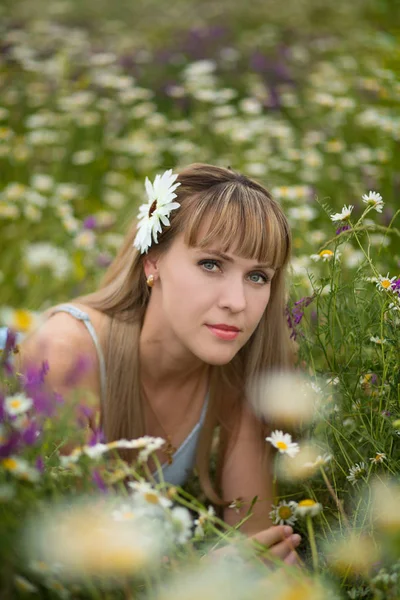 Mulher bonita desfrutando de campo de margarida, fêmea agradável deitado no prado de flores, menina bonita relaxante ao ar livre, se divertindo, segurando planta, jovem senhora feliz e natureza verde primavera, conceito de harmonia — Fotografia de Stock