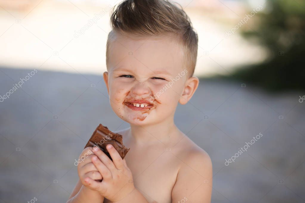 Child eats chokolate with full stength on a beach