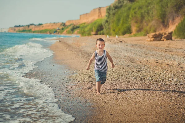 Хлопчик біжить на прекрасному пляжі. Хлопчик гуляє на прекрасному пляжі. Морська піна на піску. стосунки способу життя контакт родовідного походження — стокове фото