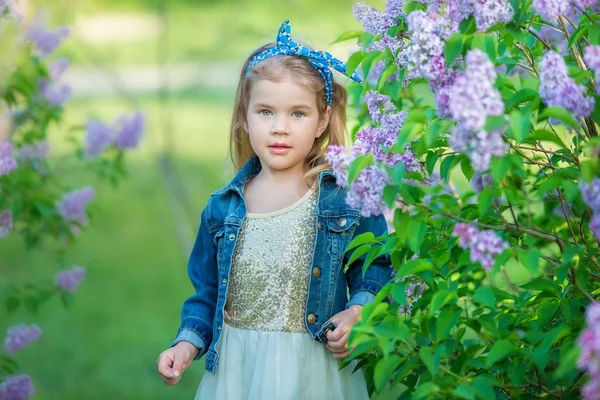 Cute girl in blue jackets with fairy airy skirt standing close to lilac bush — Stock Photo, Image