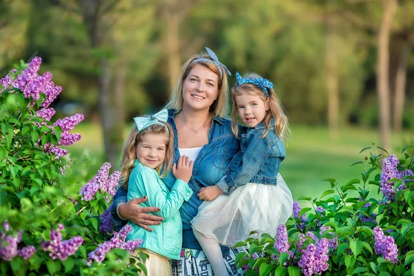 Anya nő két aranyos mosolygós lány nővérek szép együtt a lila mező bush minden elegáns ruhák és farmer kabátot viselt. — Stock Fotó