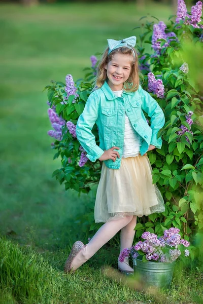 Menina bonito em jaquetas azuis com saia de fada arejada de pé perto do arbusto lilás — Fotografia de Stock