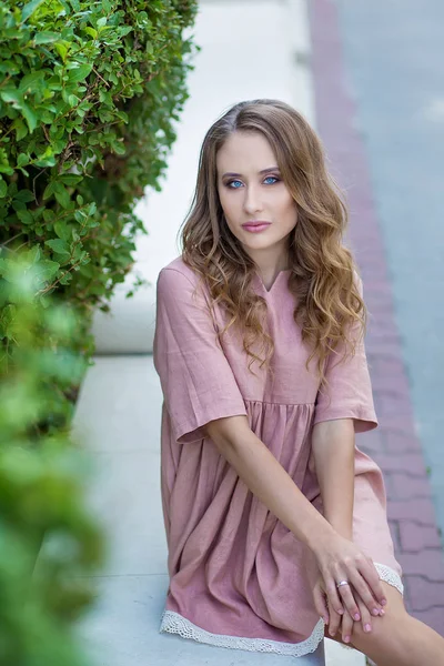 Sensuale affascinante ritratto soleggiato di splendida splendida donna elegante in posa nel centro della città europea. Cappotto bianco classico, vestitino nero, sorriso magnifico. Tramonto, colori serali . — Foto Stock