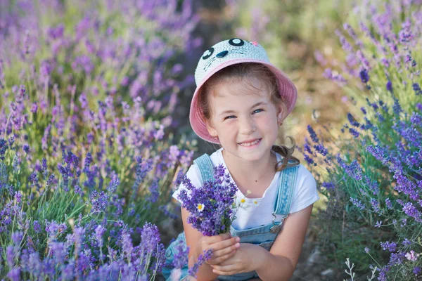 Menina em um chapéu de palha em um campo de lavanda com uma cesta de lavanda. Uma rapariga num campo de lavanda. Menina com um buquê de lavanda . — Fotografia de Stock