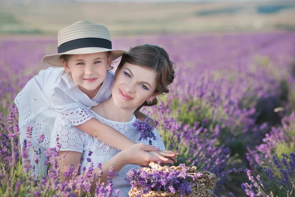 A gyönyörű fiatal hölgy édesanyja, a szép lánya, séta a levendula mező egy hétvégi napon a csodálatos ruhák és kalapok. — Stock Fotó