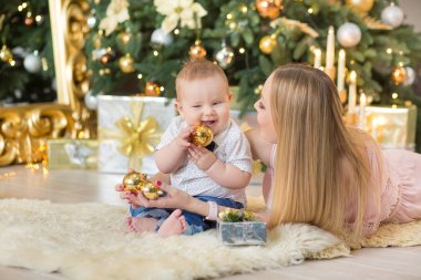 mutlu aile anne ve bebek eve Noel tatili üzerinde oynarken küçük oğlu. Toddler anne Noel ağacı ile festively bir şekilde dekore edilmiş oda ile. Portre rahat kıyafetler anne ve bebek çocuk