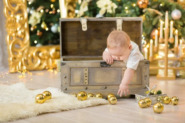 O lindo menino celebra o Natal. Férias de Ano Novo. Bebê em um traje de Natal roupas casuais com presentes na pele perto da árvore de ano novo em decorações de estúdio . — Fotografia de Stock