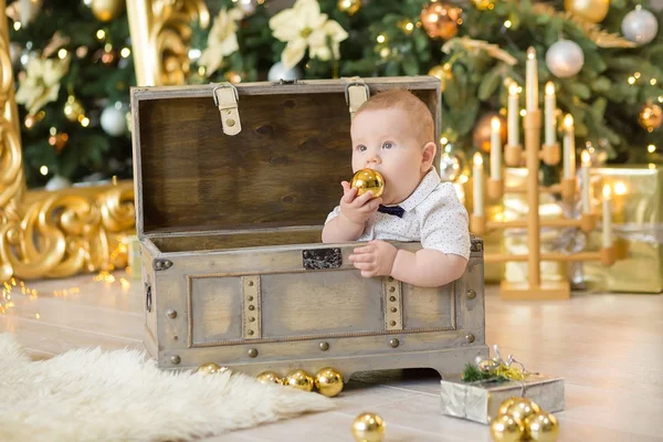 O lindo menino celebra o Natal. Férias de Ano Novo. Bebê em um traje de Natal roupas casuais com presentes na pele perto da árvore de ano novo em decorações de estúdio . — Fotografia de Stock