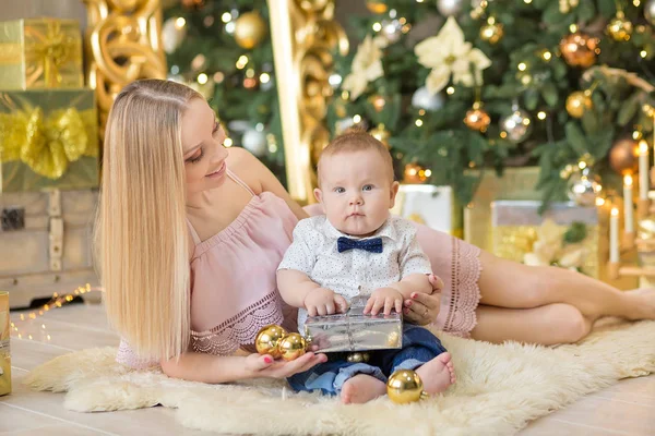 Ευτυχισμένη οικογένεια μητέρα και το μωρό ο μικρός γιος παίζει σπίτι στις διακοπές των Χριστουγέννων. Νήπια με τη μαμά στην αίθουσα γιορταστικά διακόσμησα με Χριστουγεννιάτικο δέντρο. Πορτρέτο της μαμά και το μωρό αγόρι σε casual ρούχα — Φωτογραφία Αρχείου