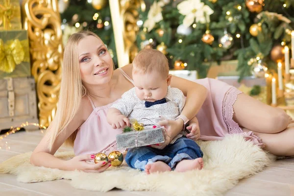 Ευτυχισμένη οικογένεια μητέρα και το μωρό ο μικρός γιος παίζει σπίτι στις διακοπές των Χριστουγέννων. Νήπια με τη μαμά στην αίθουσα γιορταστικά διακόσμησα με Χριστουγεννιάτικο δέντρο. Πορτρέτο της μαμά και το μωρό αγόρι σε casual ρούχα — Φωτογραφία Αρχείου