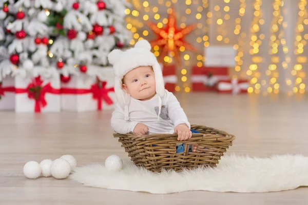 Vackra lilla pojke firar jul. Nya årets semester. Barnet i en jul kostym casual kläder med presenter på päls nära nyår träd i studio dekorationer. — Stockfoto
