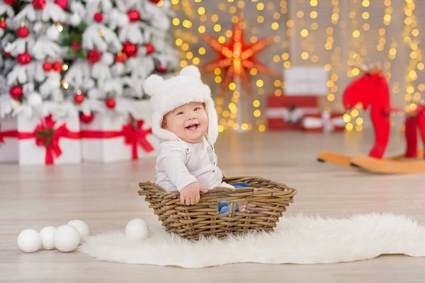 O lindo menino celebra o Natal. Férias de Ano Novo. Bebê em um traje de Natal roupas casuais com presentes na pele perto da árvore de ano novo em decorações de estúdio . — Fotografia de Stock