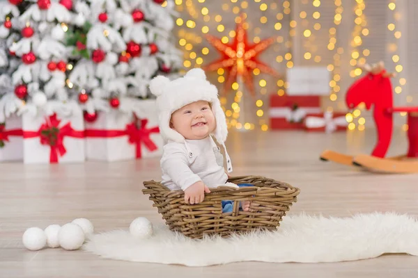 O lindo menino celebra o Natal. Férias de Ano Novo. Bebê em um traje de Natal roupas casuais com presentes na pele perto da árvore de ano novo em decorações de estúdio . — Fotografia de Stock