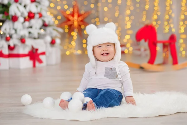 O lindo menino celebra o Natal. Férias de Ano Novo. Bebê em um traje de Natal roupas casuais com presentes na pele perto da árvore de ano novo em decorações de estúdio . — Fotografia de Stock