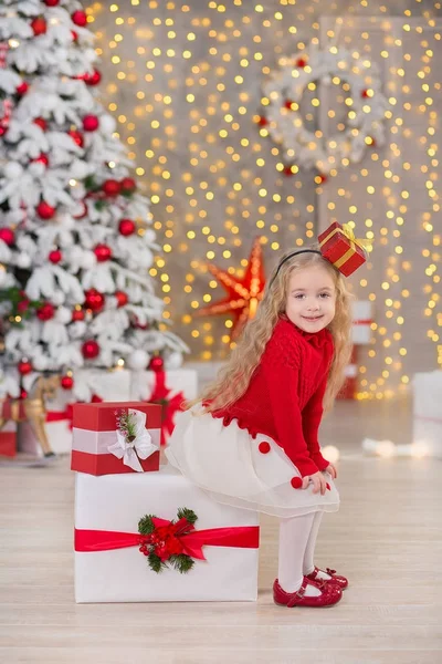 Young beautiful girl smiling, sitting near huge golden mirror plenty presents on fur Christmas green white luxury tree decorations and beneath lie gifts — Stock Photo, Image