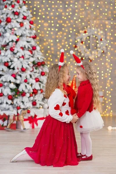Retrato de Natal de duas lindas meninas bonitas irmãs sorridentes amigos e xmas luxo verde árvore branca em estúdio interior único com enorme espelho dourado e pele — Fotografia de Stock