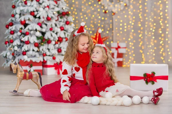 Retrato de Natal de duas lindas meninas bonitas irmãs sorridentes amigos e xmas luxo verde árvore branca em estúdio interior único com enorme espelho dourado e pele — Fotografia de Stock