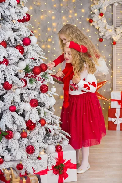 Kerst portret van twee beautyful leuke meisjes Smiling zusters vrienden en luxe groen witte kerstboom in unieke interieur studio met enorme gouden spiegel en bont — Stockfoto