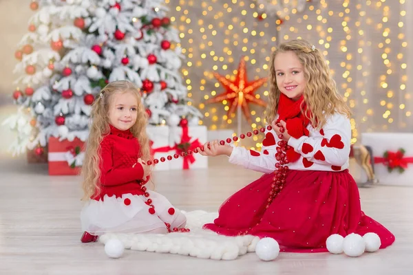 Retrato de Natal de duas lindas meninas bonitas irmãs sorridentes amigos e xmas luxo verde árvore branca em estúdio interior único com enorme espelho dourado e pele — Fotografia de Stock