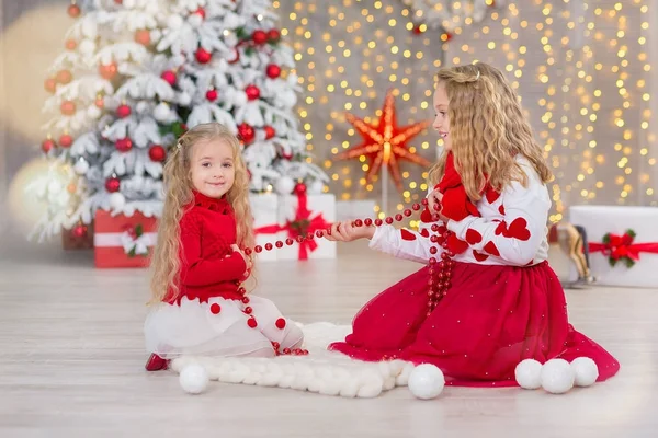 Χριστούγεννα πορτρέτο του όμορφο δύο χαριτωμένα κορίτσια Smiling αδελφές φίλοι και Χριστούγεννα Πολυτελές Πράσινο λευκό δέντρο στο μοναδικό εσωτερικό στούντιο με τεράστιο χρυσό καθρέφτη και γούνα — Φωτογραφία Αρχείου