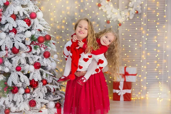 Retrato de Natal de duas lindas meninas bonitas irmãs sorridentes amigos e xmas luxo verde árvore branca em estúdio interior único com enorme espelho dourado e pele — Fotografia de Stock