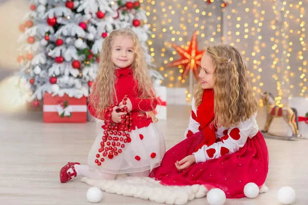 Retrato de Natal de duas lindas meninas bonitas irmãs sorridentes amigos e xmas luxo verde árvore branca em estúdio interior único com enorme espelho dourado e pele — Fotografia de Stock