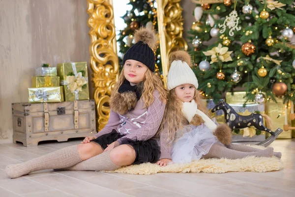Kerst portret van twee beautyful leuke meisjes Smiling zusters vrienden en luxe groen witte kerstboom in unieke interieur studio met enorme gouden spiegel en bont — Stockfoto