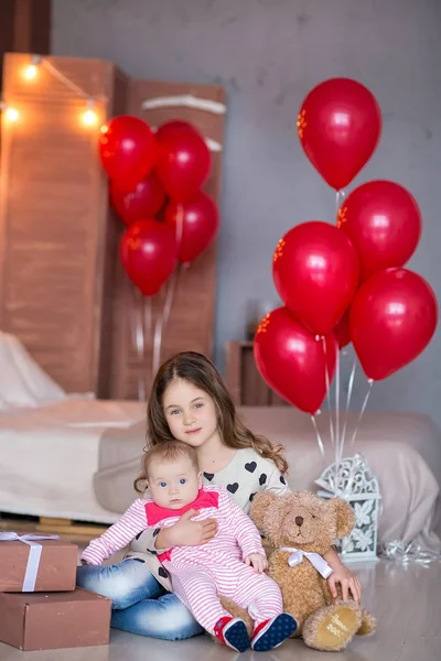 Söt baby flicka firar födelse dag tillsammans nära röda ballonger. Härlig scen av baby på soffa divan med presenter och röda baloons. — Stockfoto