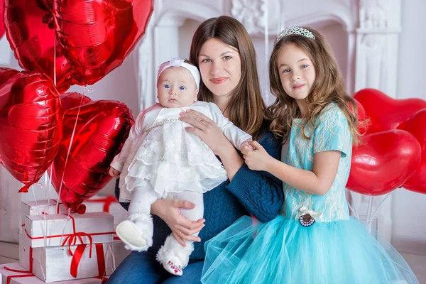 Beautiful young mother and daughter in dresses with wreathes on their hads with colorful baloons in photo studio — Stock Photo, Image