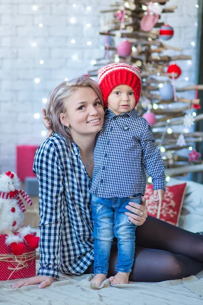 Πορτρέτο της ευτυχισμένης μητέρας και αξιολάτρευτο μωρό γιορτάζουν τα Χριστούγεννα. Πρωτοχρονιάτικες διακοπές. Βρέφος με τη μαμά στο εορταστικά διακοσμημένο δωμάτιο με χριστουγεννιάτικο δέντρο και διακοσμήσεις. — Φωτογραφία Αρχείου
