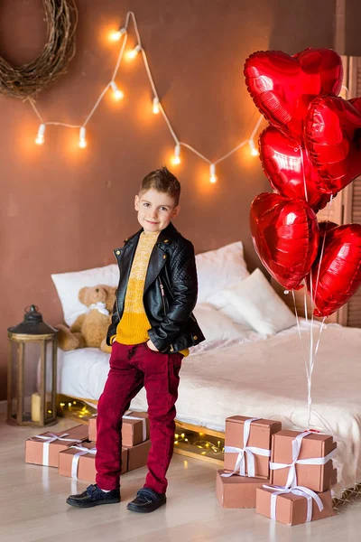 Snygg hipster tonåring poserar med rött hjärta ballong i studio. Ung man i gul skjorta gå till datumet över studio bakgrund. — Stockfoto