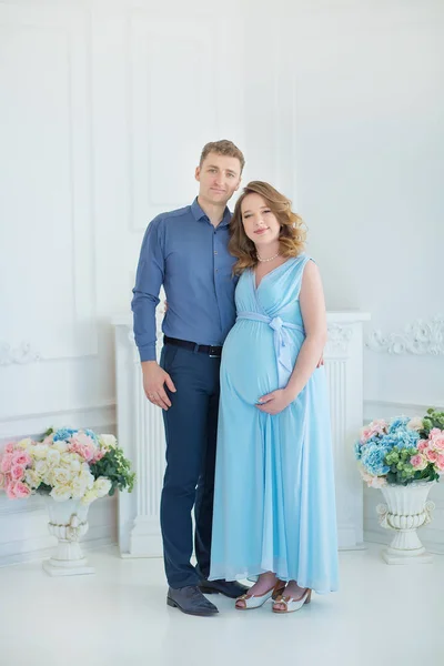 Un cuplu fericit de părinți care se uită la un pantof roșu drăguț pentru copilul lor nenăscut, portret de studio în interior — Fotografie, imagine de stoc