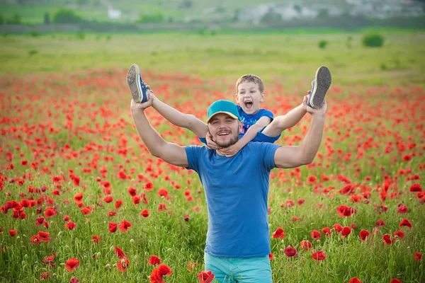 Schöner Vater zusammen mit glücklich lächelndem Sohn und englischem Bulldog auf einem Mohnfeld. — Stockfoto