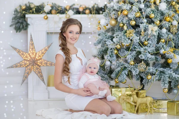 Mãe mãe com um pouco de doce e bela filha passa o tempo brincadeiras, coos, sentado ao lado da árvore de Natal — Fotografia de Stock