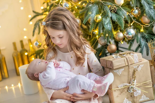 Οικογένεια την παραμονή των Χριστουγέννων στο τζάκι. Τα παιδιά Χριστούγεννα παρουσιάζει εγκαίνια. Τα παιδιά κάτω από το χριστουγεννιάτικο δέντρο με κουτιά δώρων. Διακοσμημένο σαλόνι-καθιστικό με παραδοσιακό τζάκι. Ζεστό ζεστό χειμωνιάτικο απόγευμα στο σπίτι. — Φωτογραφία Αρχείου