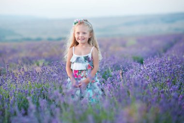 Lavanta sahada gülümseyen genç kızı ile genç anne. Kızı anne eller üzerinde oturuyor. Renkli elbise ve koyu mavi elbiseli anne kız.
