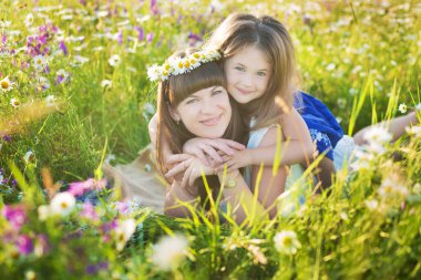 Anne ve kızı bir piknik papatya alanındaki tarih. At bir arka plan üzerinde papatya alanında iki güzel sarışın. Anne ve kızı papatya alanında kucaklayan