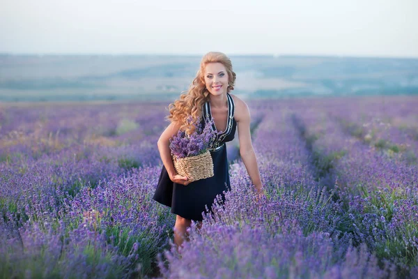 Lavanta sahada gülümseyen genç kızı ile genç anne. Kızı anne eller üzerinde oturuyor. Renkli elbise ve koyu mavi elbiseli anne kız.