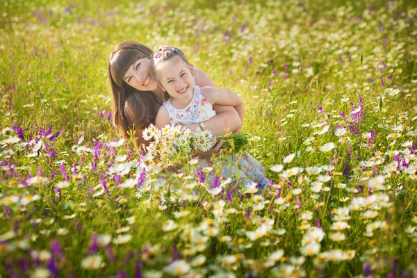 Мама и дочь на пикнике на ромашковом поле. Две красивые блондинки в ромашковом поле на фоне лошади. Мать и дочь обнимаются в ромашковом поле — стоковое фото