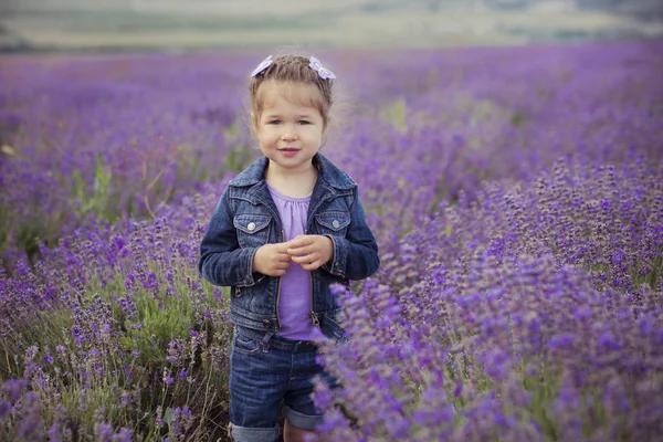 Menina bonita sentada no campo de lavanda em barco chapéu agradável com flor roxa sobre ele . — Fotografia de Stock