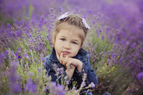 Bella ragazza seduta nel campo di lavanda in bel cappello da barca con fiore viola su di esso . — Foto Stock