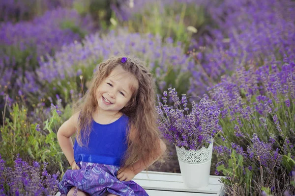 Menina bonita sentada no campo de lavanda em barco chapéu agradável com flor roxa sobre ele . — Fotografia de Stock