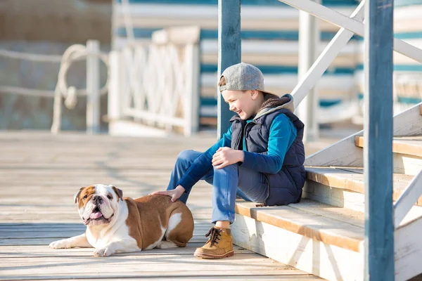 Trevlig ser stilig pojke på stranden med bulldog — Stockfoto