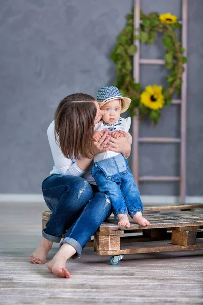 Eine glückliche Mutter und ihre kleine Tochter haben Spaß. Sie lachen beide. Sie tragen lässige Kleidung und florale Kränze an. die Atmosphäre des Glücks ist überall um sie herum. — Stockfoto