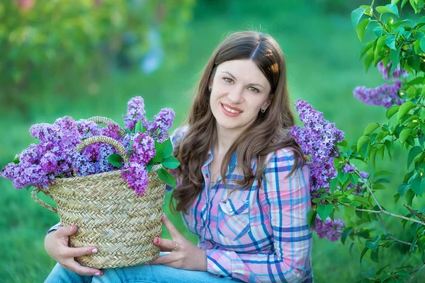 Krásná žena těší šeříková zahrada, mladá žena s květinami v zeleném parku. dívka trhá lila v zahradě — Stock fotografie