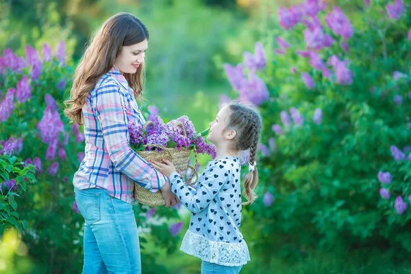 Siostry z matka, grając w ogrodzie kwitnące bzu. Słodkie dziewczynki z kiść bzu w kwiat. Dziecko ciesząc się szczęśliwe dzieciństwo. Koncepcja rodziny, miłości, pokoju i szczęścia — Zdjęcie stockowe