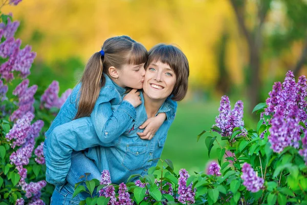 Cute adorable piękne kobieta matka pani Mama z córka brunetka dziewczyna łące fioletowy fioletowy krzew. Ludzie w nosić dżinsy. — Zdjęcie stockowe