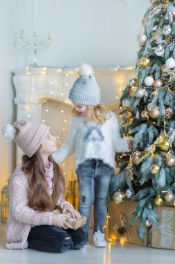 İki sevimli müthiş kız kız kardeş xmas ağacı ile şeker dolu oyuncak şık elbiseler yakın yeni yıl Noel Kutlamaları